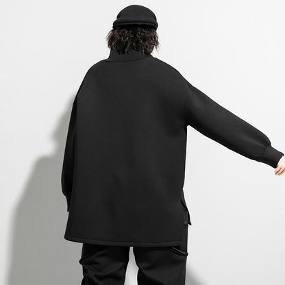 Woman wearing black oversized turtleneck pullover with utility pocket details.
