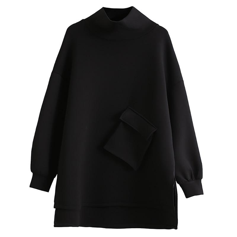 Woman wearing black oversized turtleneck pullover with utility pocket details.