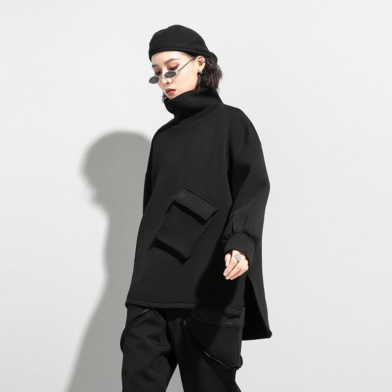 Woman wearing black oversized turtleneck pullover with utility pocket details.