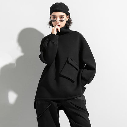 Woman wearing black oversized turtleneck pullover with utility pocket details.