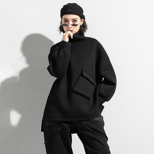 Woman wearing black oversized turtleneck pullover with utility pocket details.